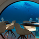 A render of the restaurant in the electric submarine with fish swimming past the windows.